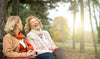 Two Older Women Laughing and Sitting on a Bench in a Park
