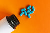 Blue Pills Layed Out Next to a Pill Bottle