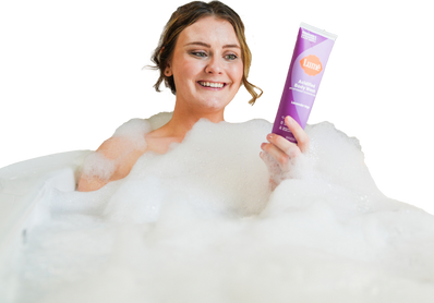 A woman in a bubbly bath holding Lume Acidified Body Wash.