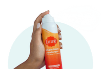 A hand sprays Lume Clean Tangerine Spray Deodorant