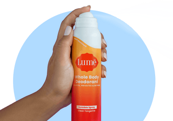 A hand sprays Lume Clean Tangerine Spray Deodorant