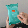 Hand pulling a wipe out of a pack of Lume deodorant wipes