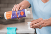 A woman pouring a capful of detergent booster