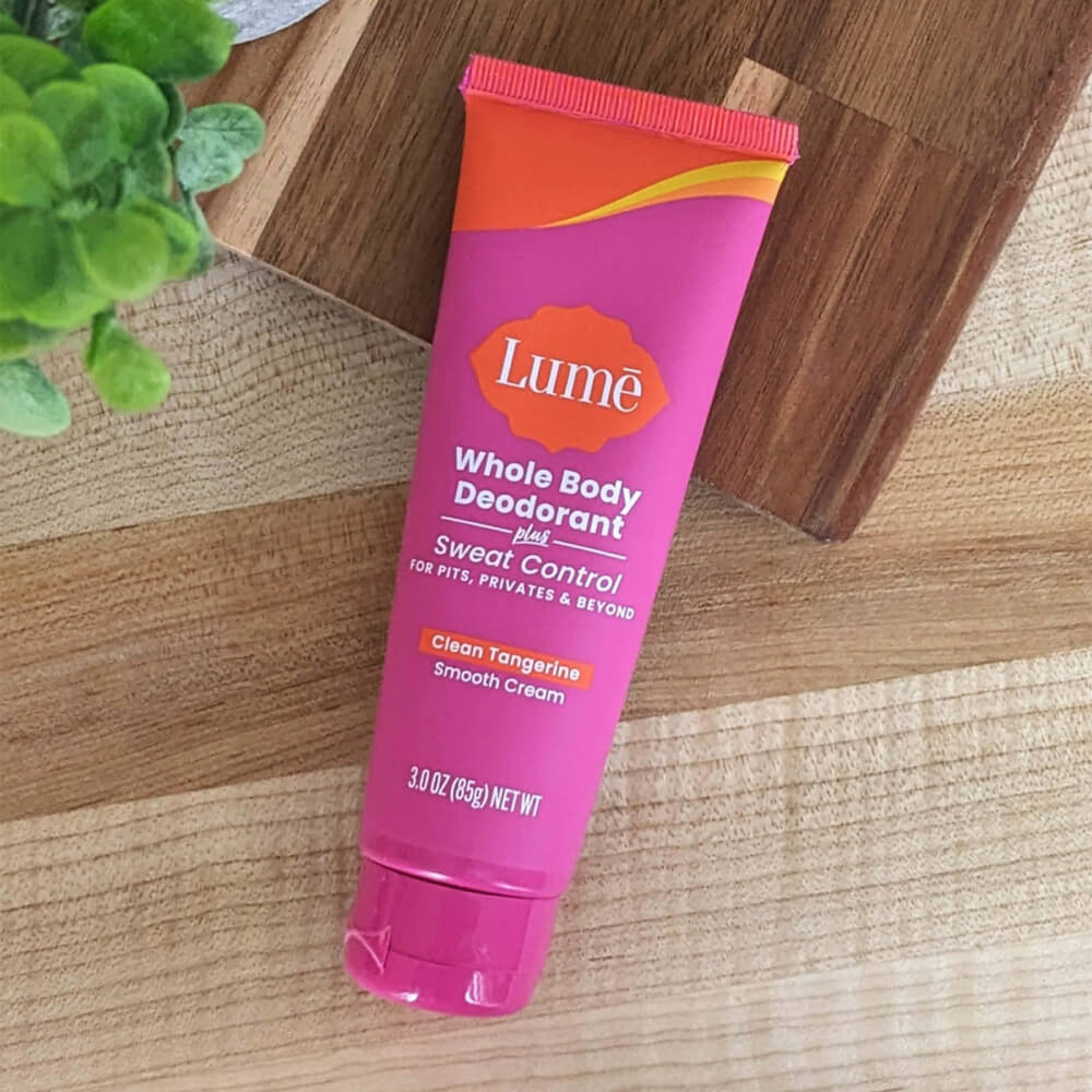 Pink and orange Lume Clean Tangerine Cream Deodorant + Sweat Control on a wooden table
