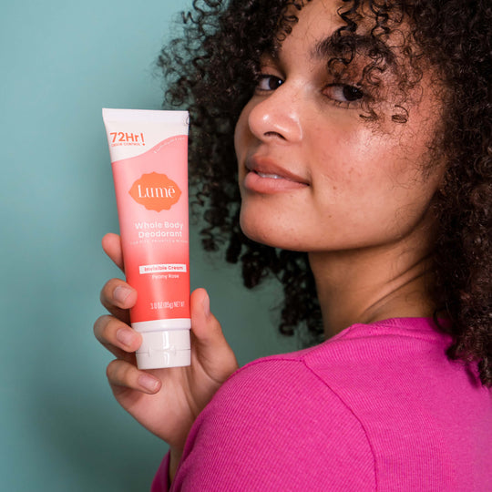 Woman holding a Pink and white Lume peony rose cream deodorant tube