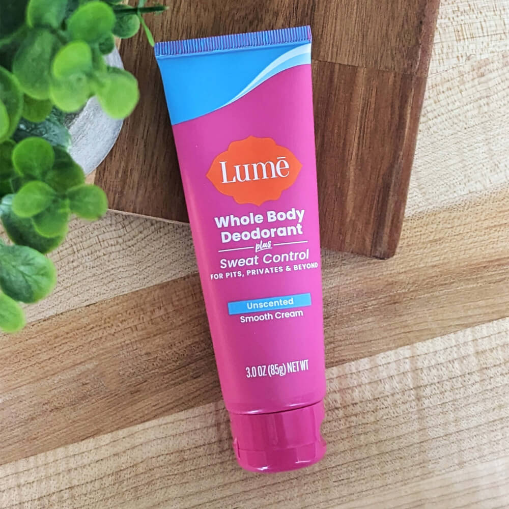 Pink and blue Lume Unscented Cream Deodorant + Sweat Control on a wooden table