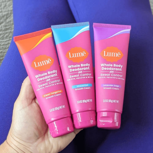 Three Lume Cream Deodorant Tubes + Sweat Control in a woman's hand in her lap